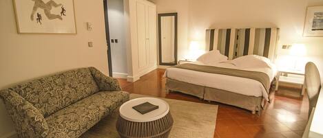 A bedroom with a bed, a sofa, a round coffee table, and a framed picture on the wall.