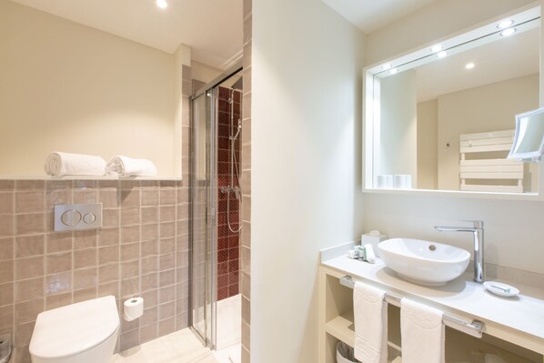 Un baño moderno con ducha envuelta en vidrio, un lavabo blanco y un espejo grande.