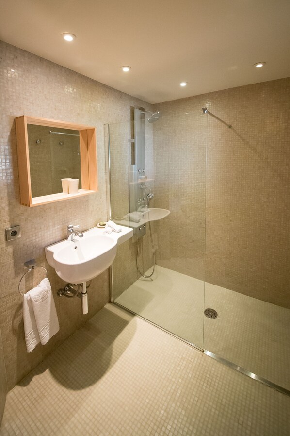 A modern bathroom with a glass-enclosed shower, a white sink, and a mirror above it.