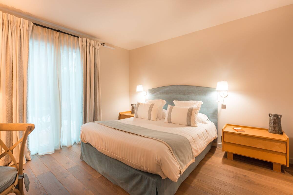 Une chambre bien rangée, avec un lit, des tables de chevet et une chaise.