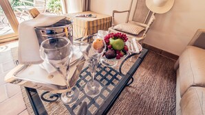 Een eethoek met een tafel gedekt voor twee personen, met een fruitschaal, wijnglazen en een kaars.