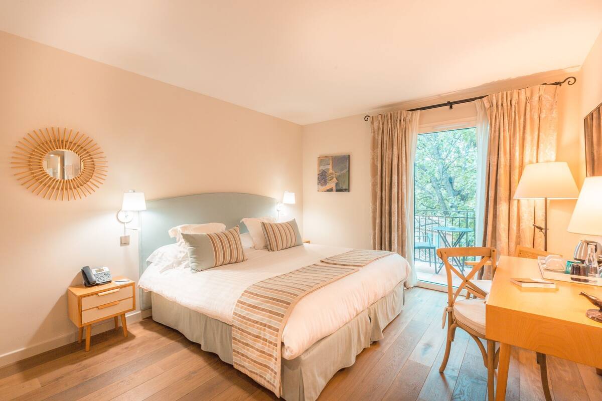 Une chambre à coucher avec un lit, des tables de chevet, une chaise et une fenêtre avec des rideaux.
