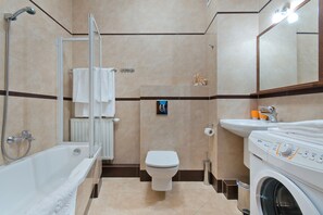 A modern bathroom with a bathtub, toilet, and washing machine. - Apartament Nadmorski Sopot 1 (Sopot)