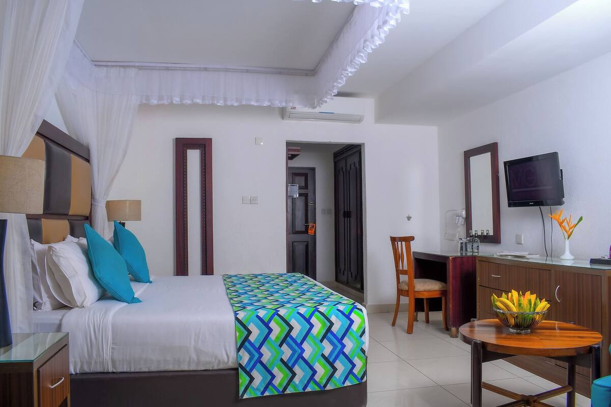 Une chambre d’hôtel équipée d’un lit, d’un bureau, d’une télévision et d’un coin repas.