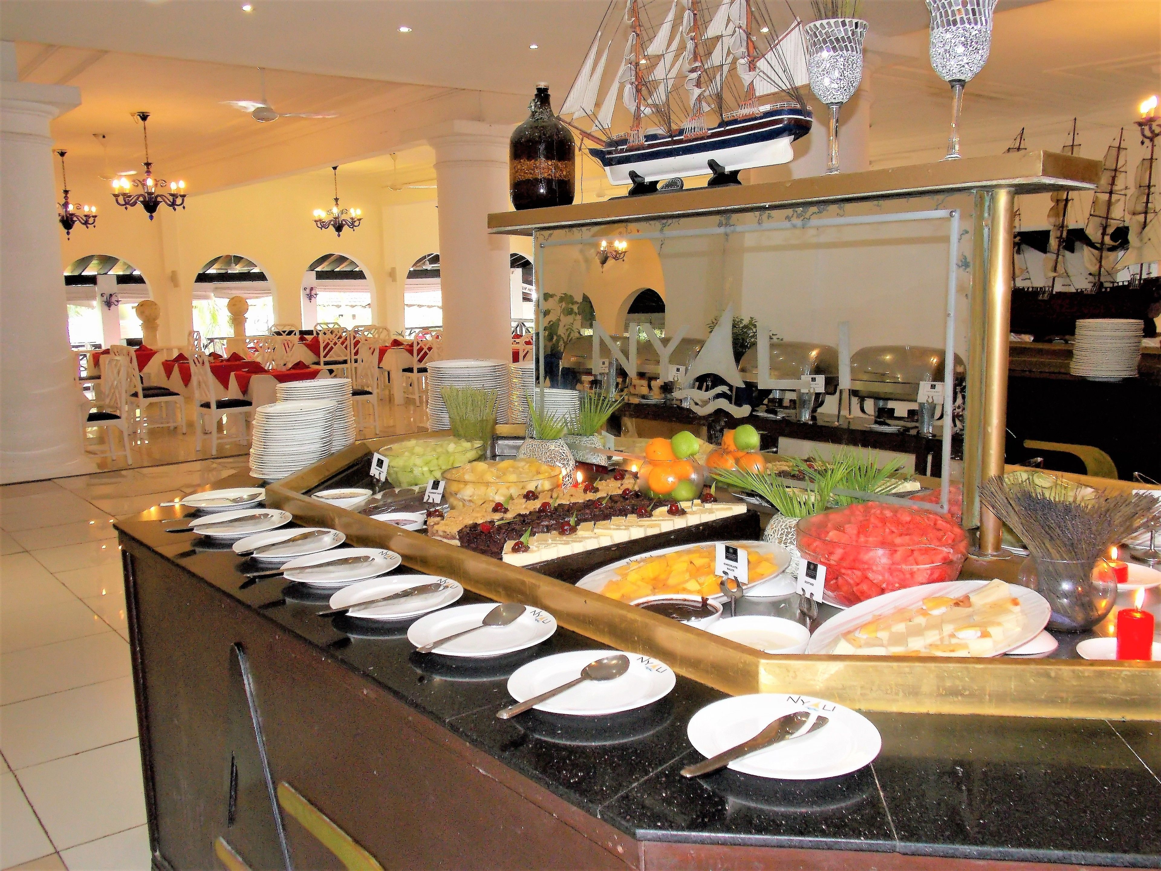 Een buffet met diverse gerechten en een decoratief model van een schip.