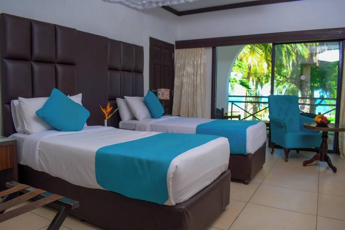 Une chambre d’hôtel avec deux lits, un balcon et une chaise.