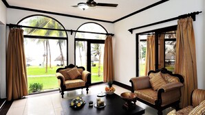 A spacious room with a ceiling fan, large windows with curtains, two sofas, and a coffee table with decorative items. - Cocoa Luxury Resort, Nyali (Mombasa)