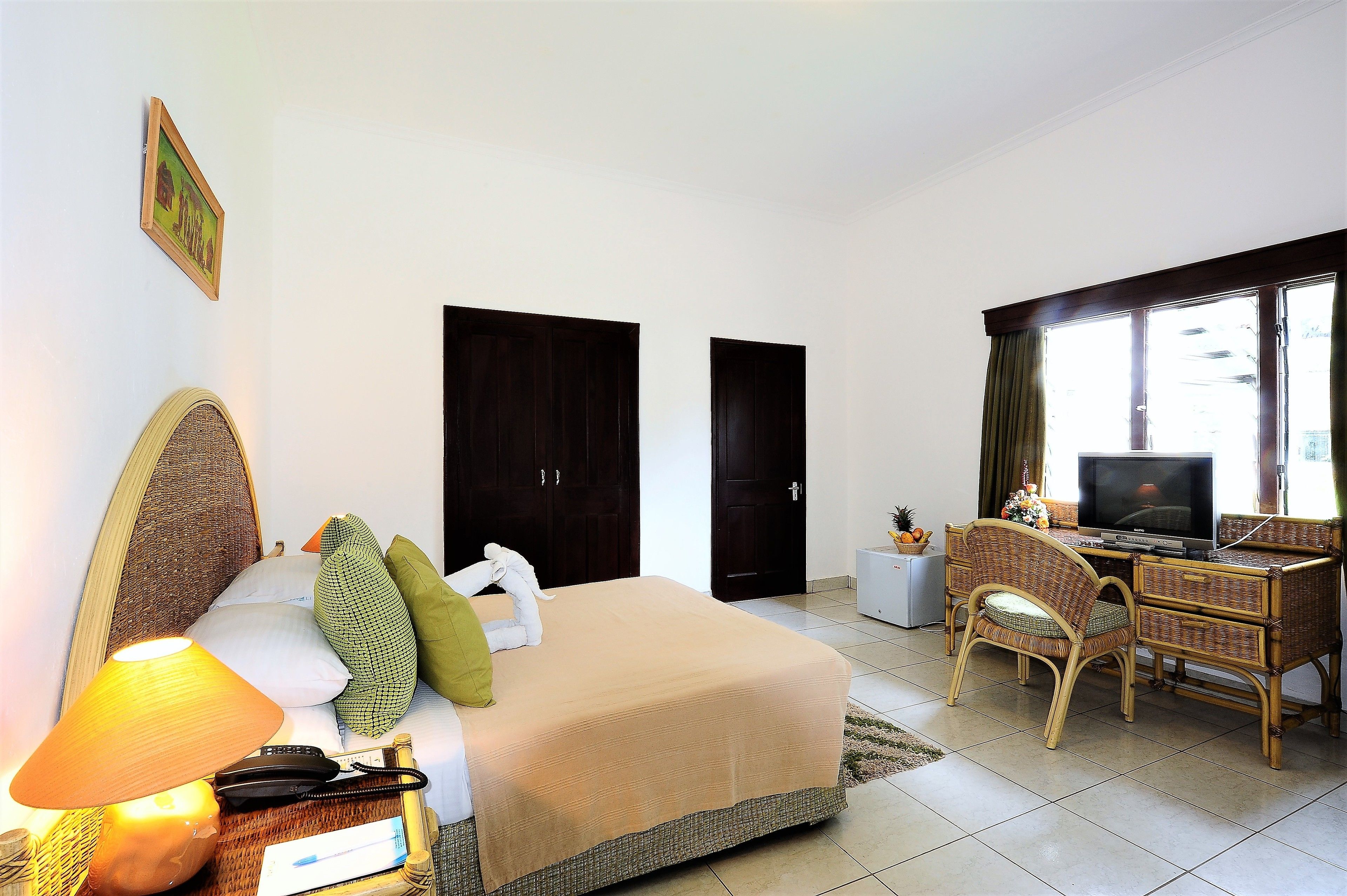 A hotel room with a bed, a desk, a television, and a window.