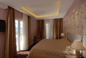 Habitación de hotel con una cama grande, una silla, un televisor y vistas al exterior.