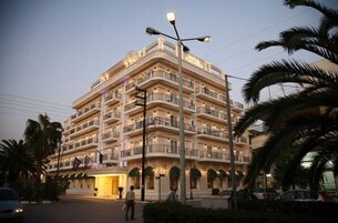 Un hotel de varios pisos con balcones, una farola y palmeras.
