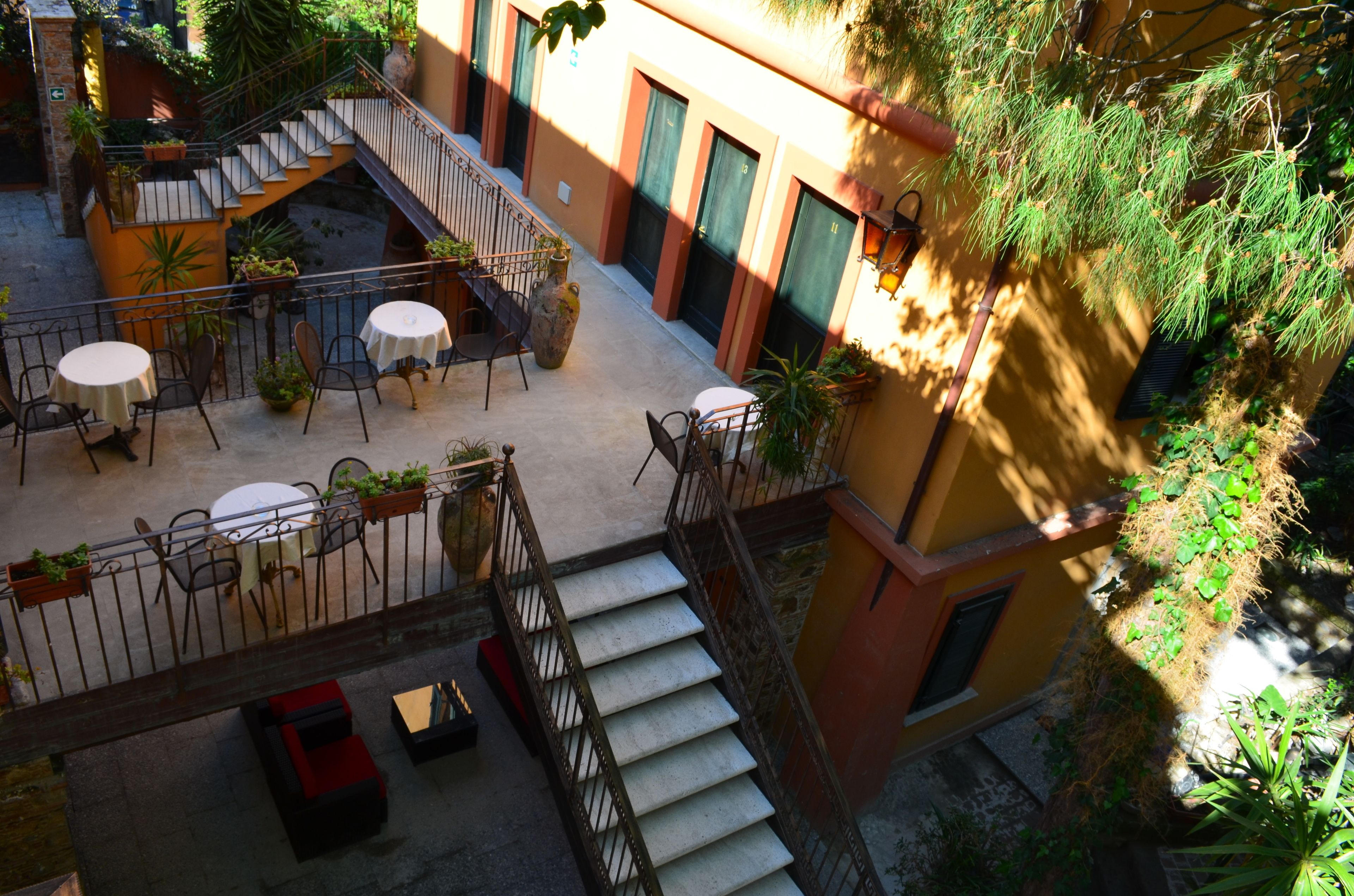 Un espace extérieur aménagé en terrasse, avec des tables et des chaises, un escalier et des plantes en pot.