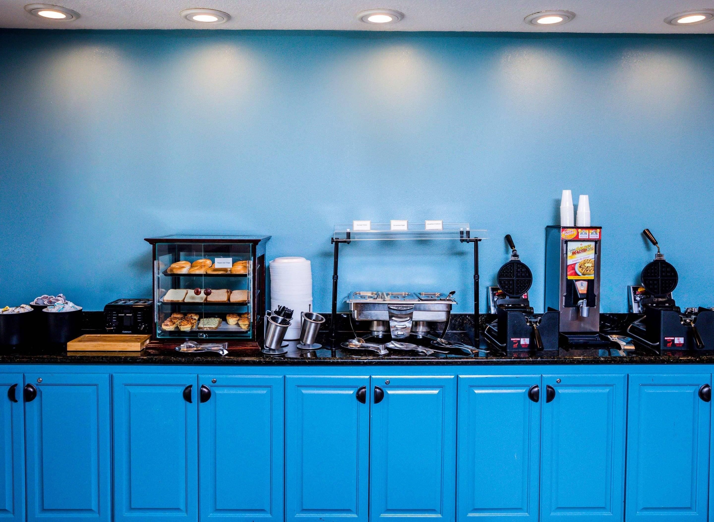 A kitchen counter with various appliances and a display case of baked goods.