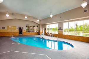Una piscina interior con agua cristalina, un trampolín y vistas al exterior a través de amplios ventanales.