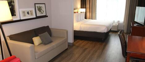 Habitación de hotel con cama, sofá, escritorio y televisor.