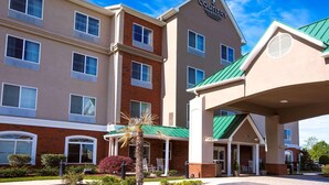 A hotel with a modern design, featuring a prominent sign for 'COUNTY INN & SUITES'. There are multiple windows on the building, and a covered entrance with a green roof. - Country Inn & Suites by Radisson, Wilson, NC (Wilson)