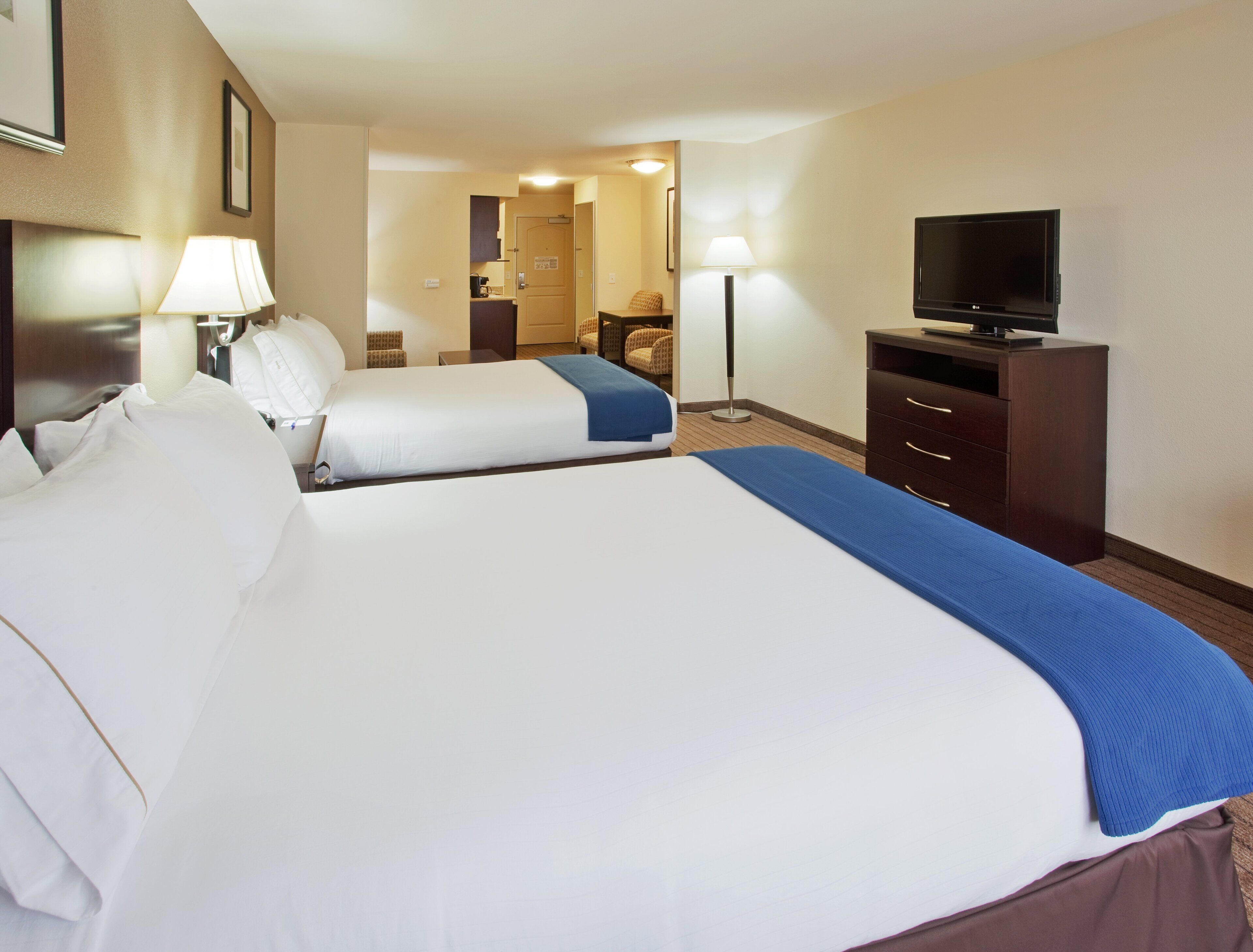 A hotel room with two beds, a TV, a desk, and a chair.