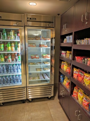 A vending area with two freezers and shelves stocked with snacks and beverages.