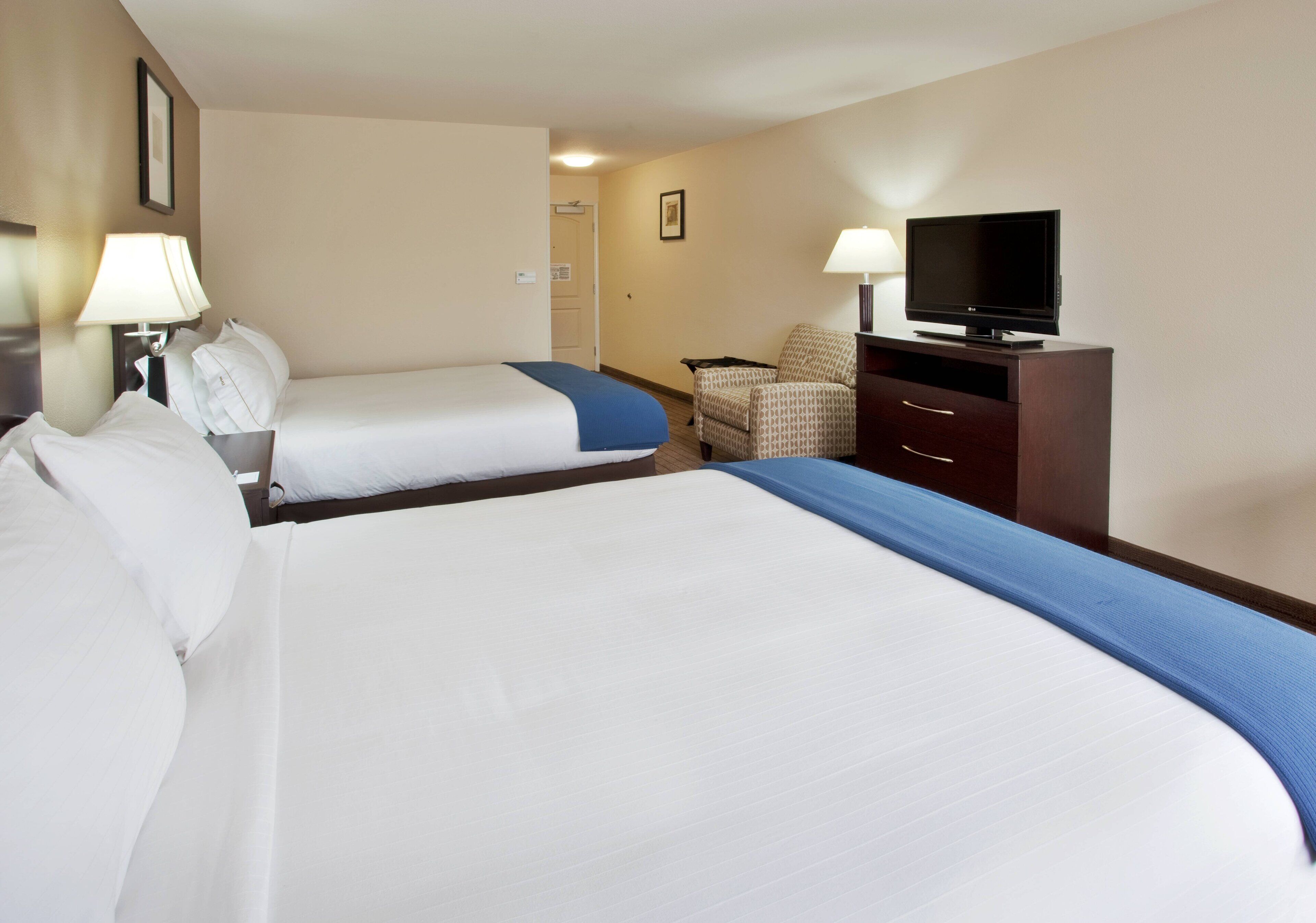 Een hotelkamer met twee bedden, een televisie, een bureau en een stoel.