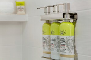 Trois bouteilles de shampooing rafraîchissant Watkins sur une étagère blanche.