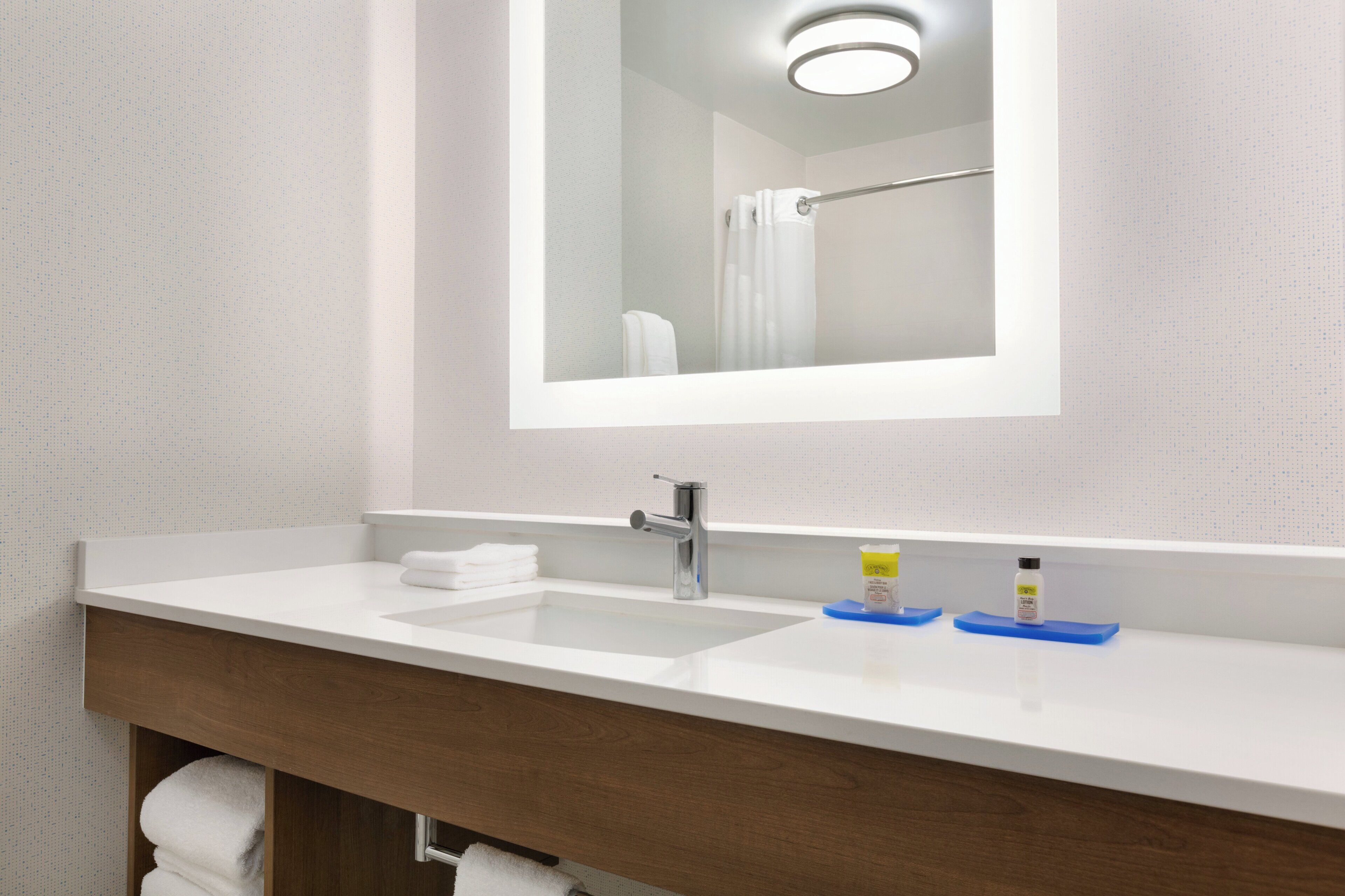 Un baño con lavamanos blanco, espejo y barra para toallas.