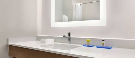 A bathroom with a white sink, a mirror, and a towel rack.