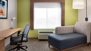A room with a desk, chair, sofa, and a window with blinds. - Holiday Inn Express Hotel & Suites Merced by IHG (Merced)