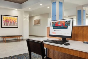 A reception desk with a computer, a bench, and framed artwork on the wall.