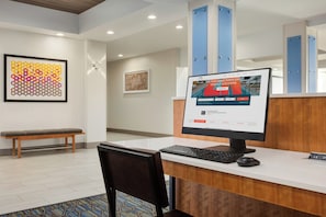 A reception desk with a computer, a bench, and framed artwork on the wall.