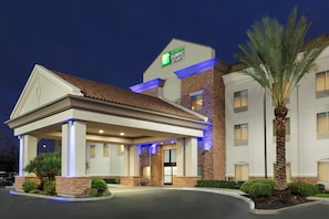 A Holiday Inn Express hotel with a covered entrance, stone facade, and palm trees.