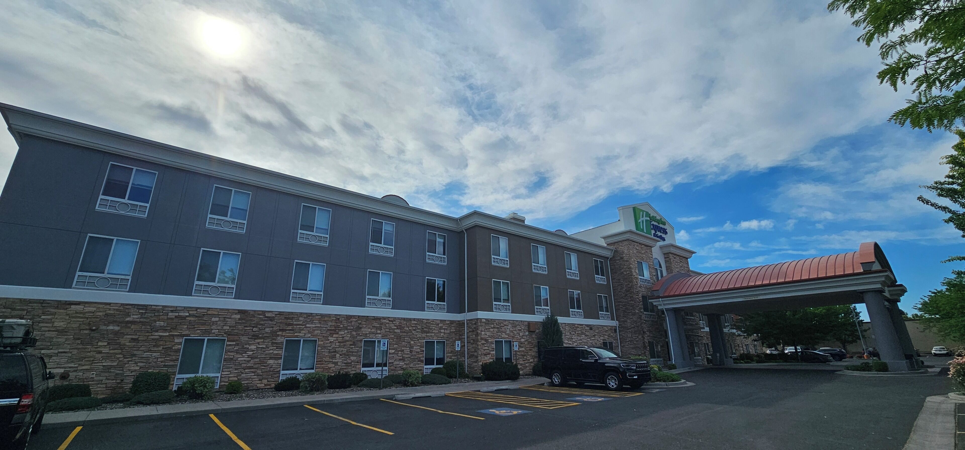 A multi-story hotel with a stone facade, a covered entrance, and a parking lot.