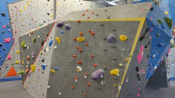 Un mur d’escalade équipé de prises de différentes couleurs et d’une corde de sécurité jaune.