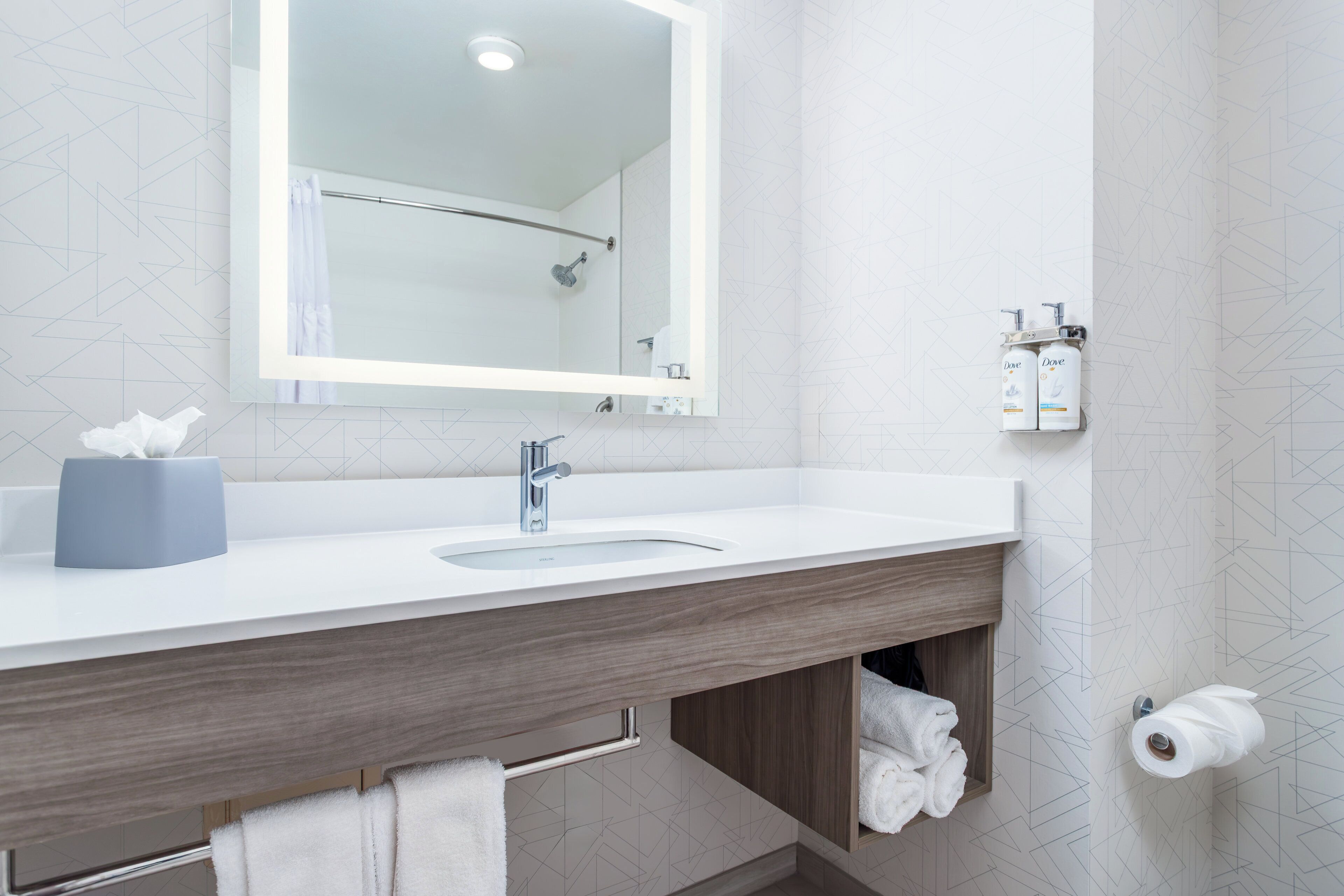 Une salle de bain moderne avec un lavabo blanc, un grand miroir et un porte-serviettes.