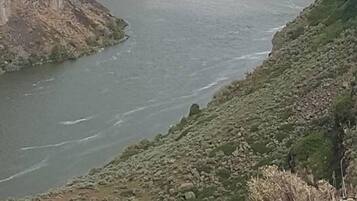 Una cascada grande se precipita a un río, rodeada de terreno rocoso y vegetación escasa.