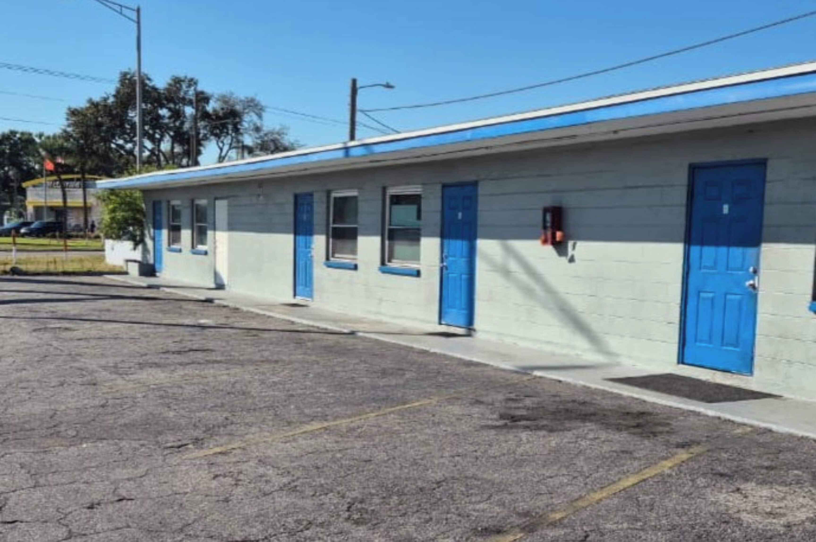 A single-story motel with a blue exterior and white walls.