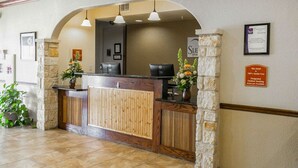 A hotel reception area with a wooden reception desk, stone pillars, and a sign indicating the hotel is 100% smoke-free. - Sleep Inn & Suites Gonzales near Palmetto State Park (Gonzales)