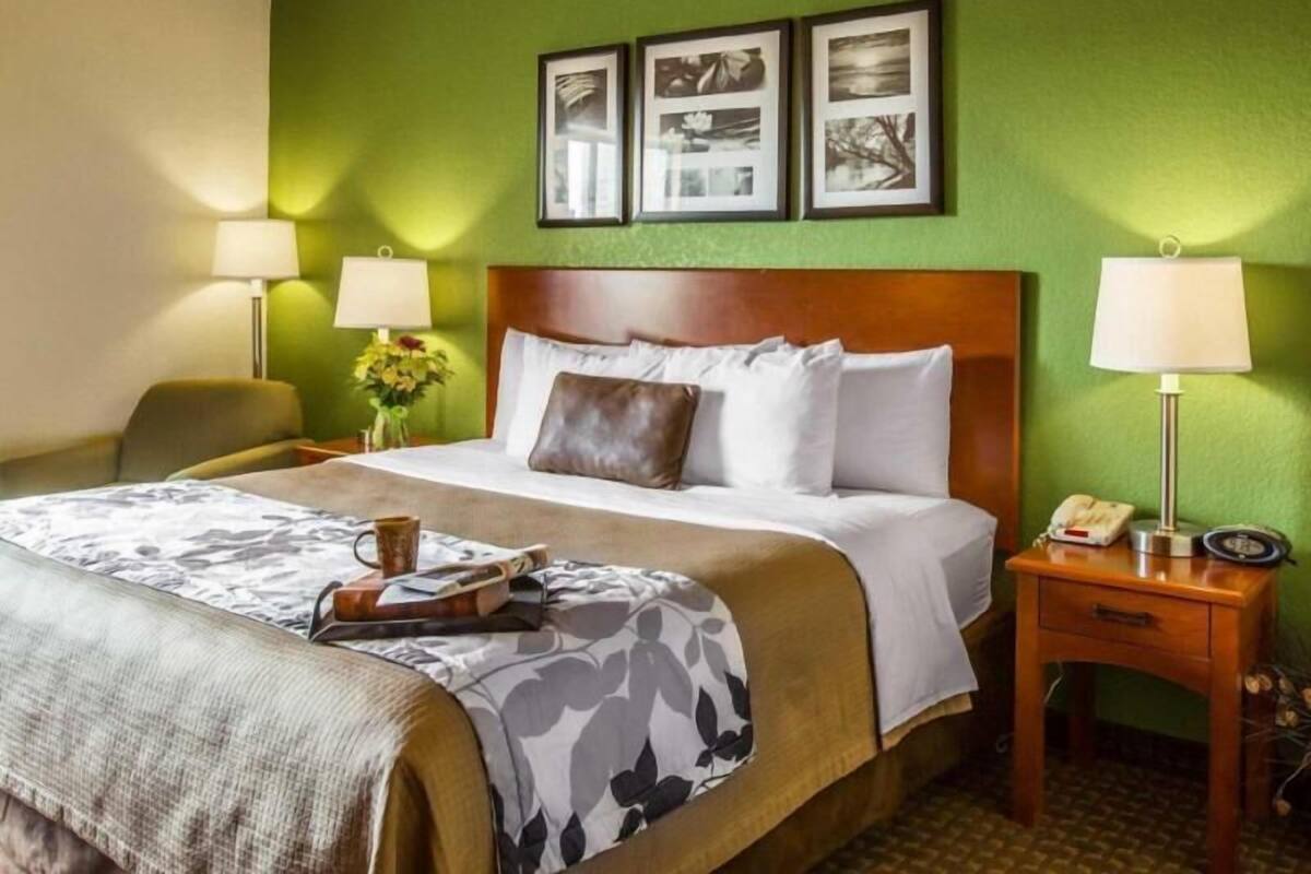 Une chambre d’hôtel avec un lit, deux tables de chevet, une chaise et des tableaux encadrés au mur.