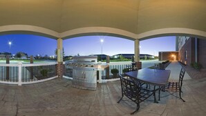 An outdoor patio with a grill, seating, and a view of a parking lot. - Candlewood Suites Lafayette by IHG (Lafayette)