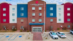 A multi-story hotel with a brick facade, a prominent entrance, and a parking lot with marked handicapped spaces. - Candlewood Suites Lafayette by IHG (Lafayette)