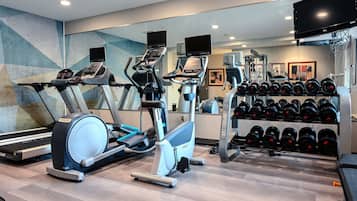 Een fitnessruimte met loopbanden, elliptische trainers en een rek met dumbbells.