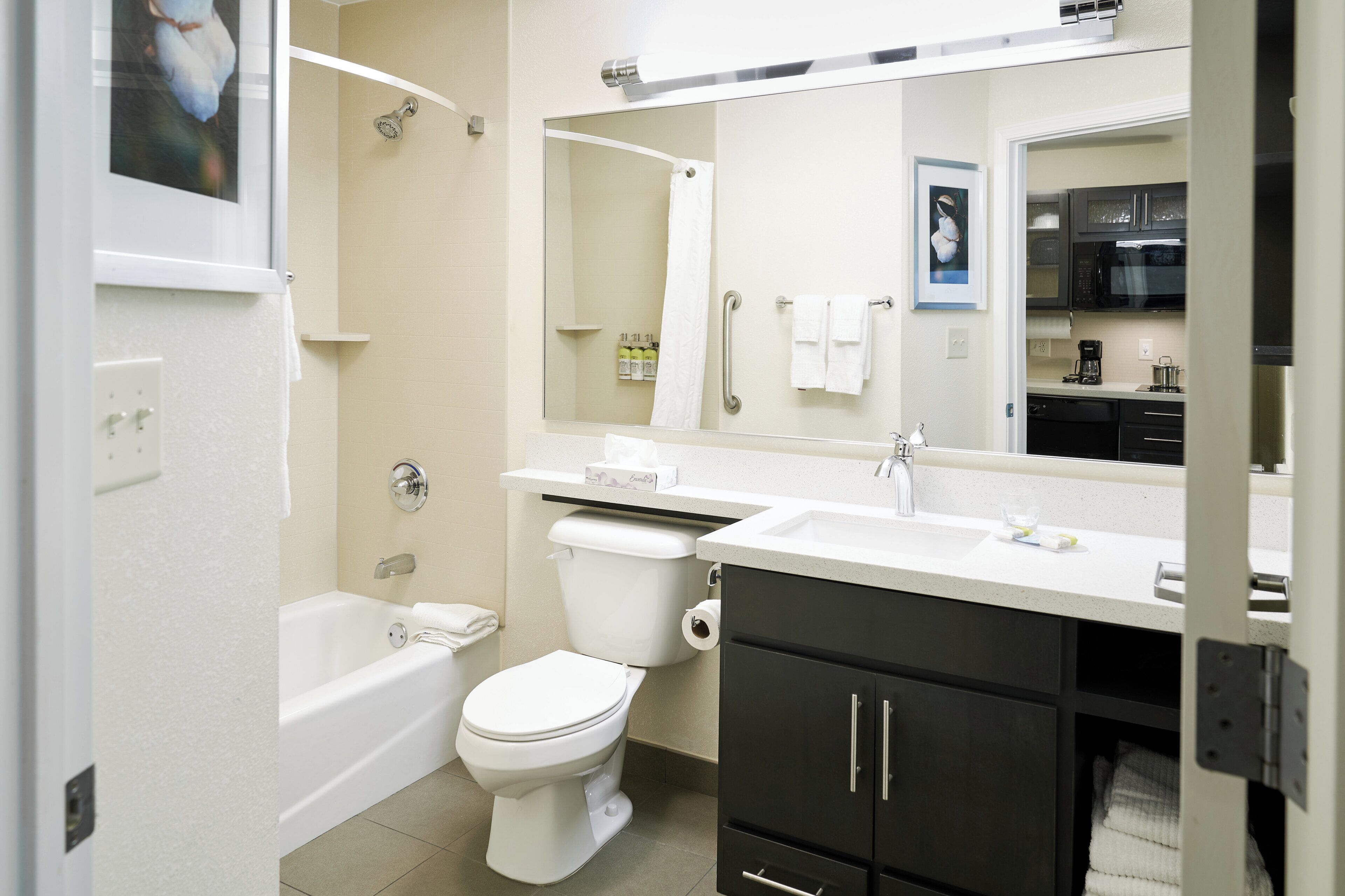 Un baño moderno con bañera, inodoro y tocador con lavamanos y espejo.