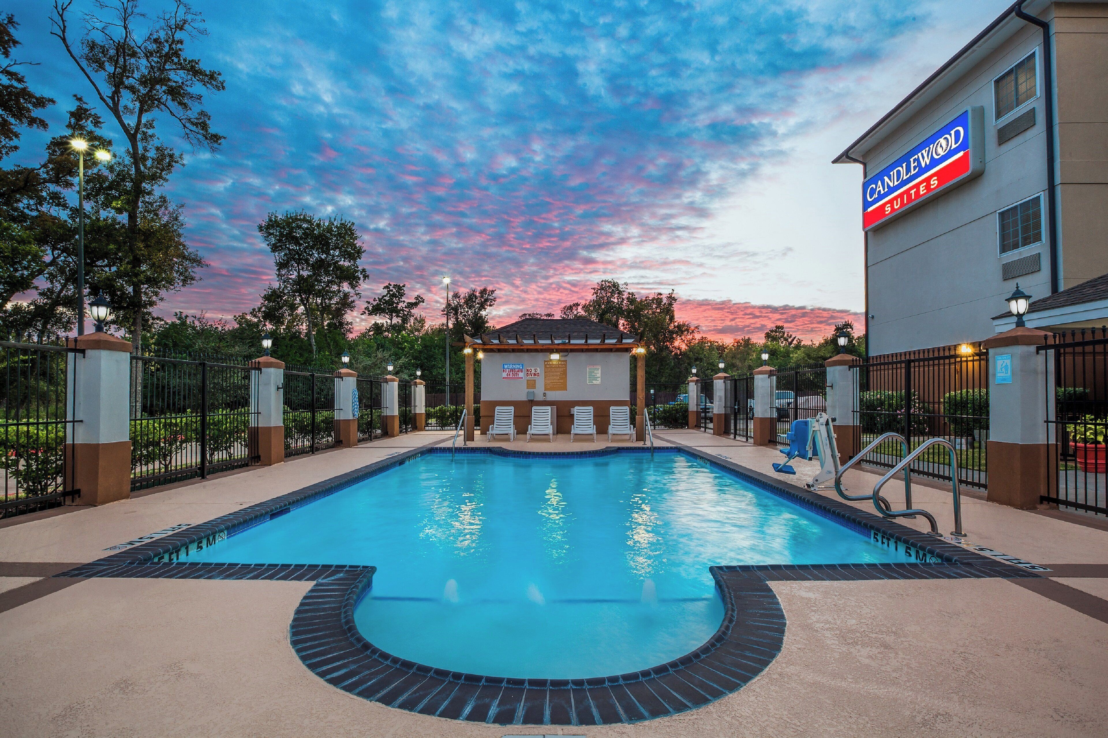 Una piscina di un hotel con cielo al tramonto, una postazione di salvataggio e un cartello per Candlewood Suites.