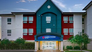 Un hotel de diseño moderno, con una entrada destacada que cuenta con un toldo azul y el nombre "Candlewood Suites".