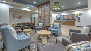 Un vestíbulo de hotel con áreas de descanso, una recepción y un separador decorativo.