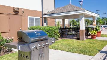 Ein Grill vor einem Gebäude mit einer überdachten Terrasse.