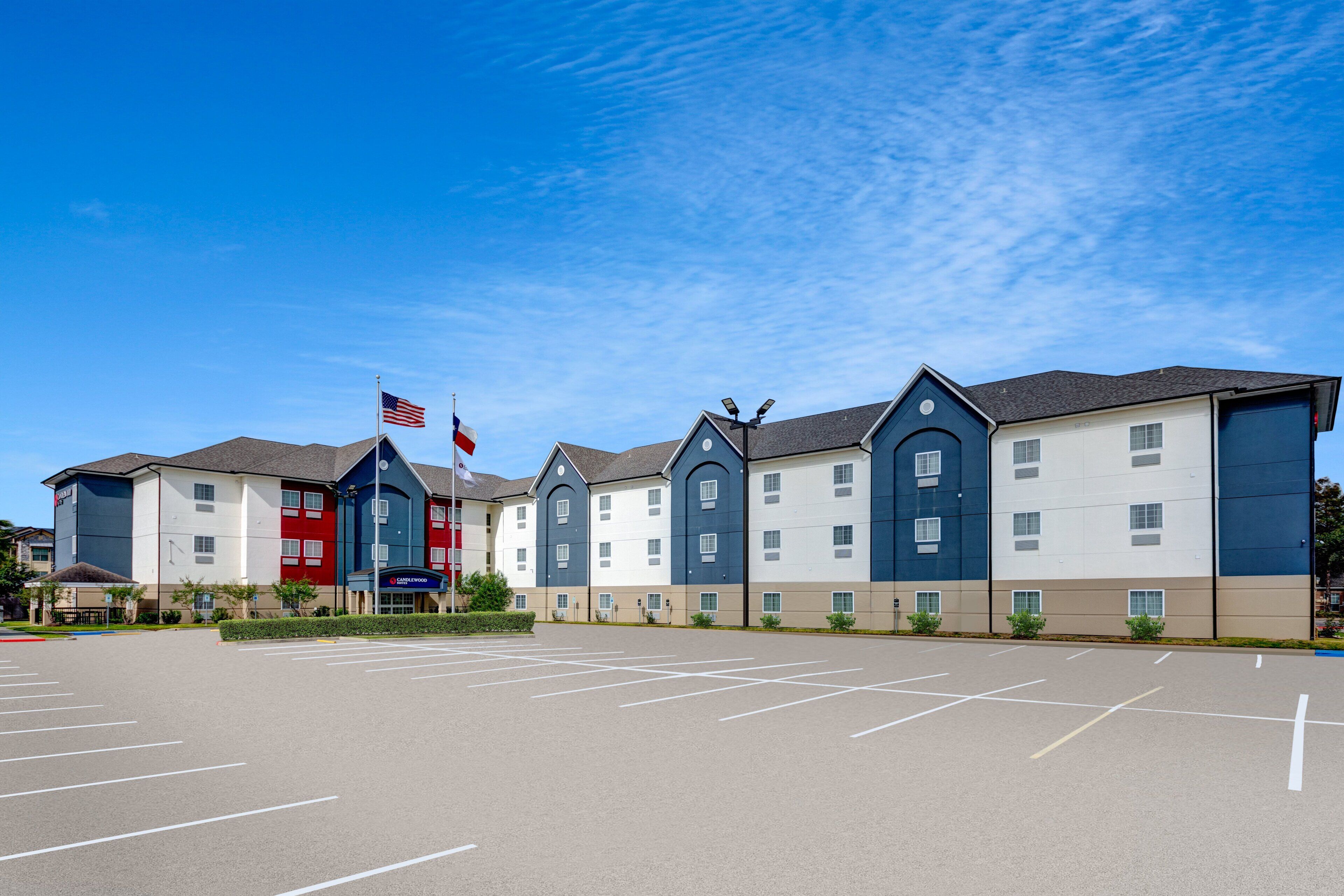 A multi-story hotel with a parking lot in front.