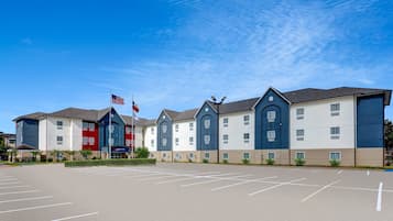 A multi-story hotel with a parking lot in front.
