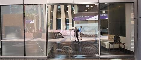 A modern building with a glass facade, a sign reading "RQ stay.", and a tiled floor.