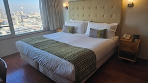 Hotelkamer met een groot bed, een nachtkastje met telefoon en uitzicht op de stad.