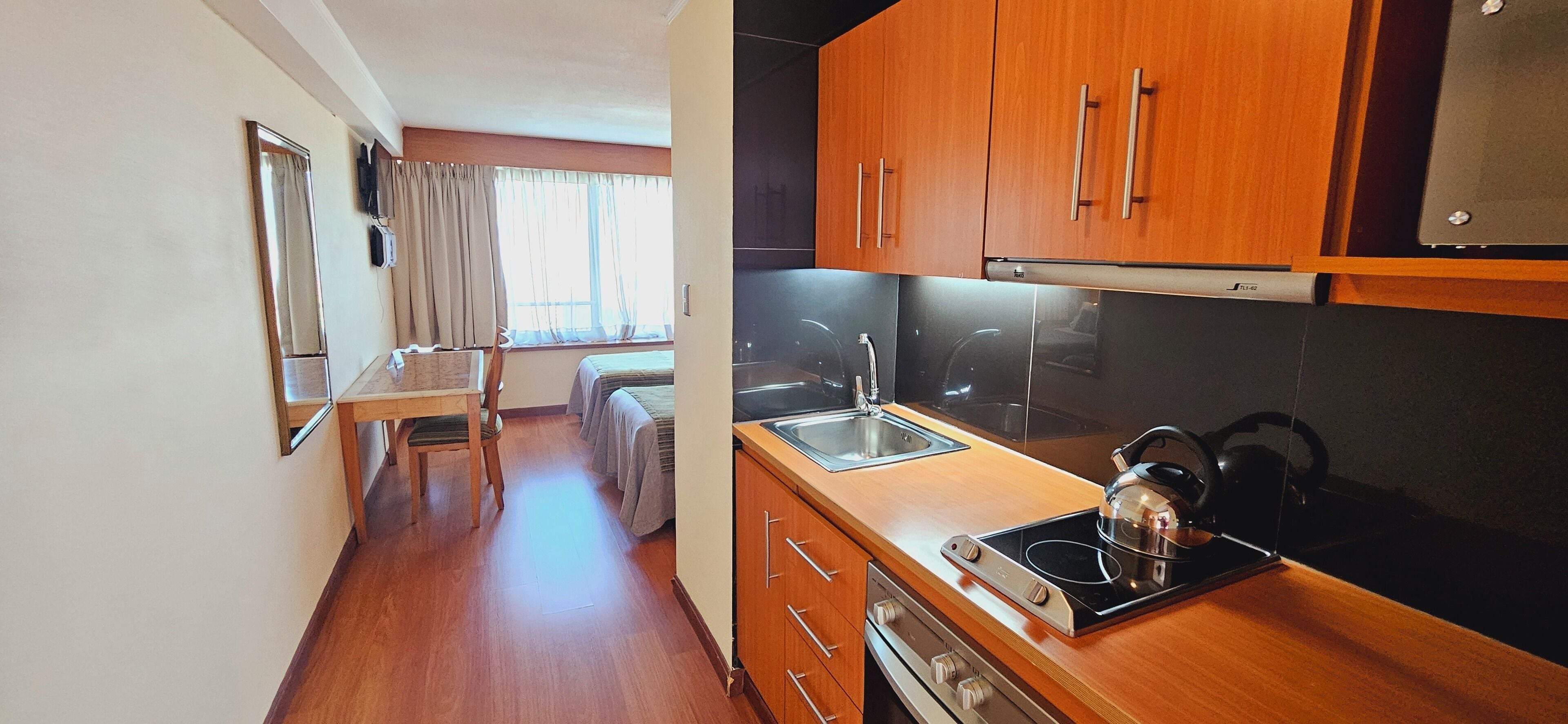 Una cocina compacta con armarios de madera, estufa empotrada y un lavamanos.
