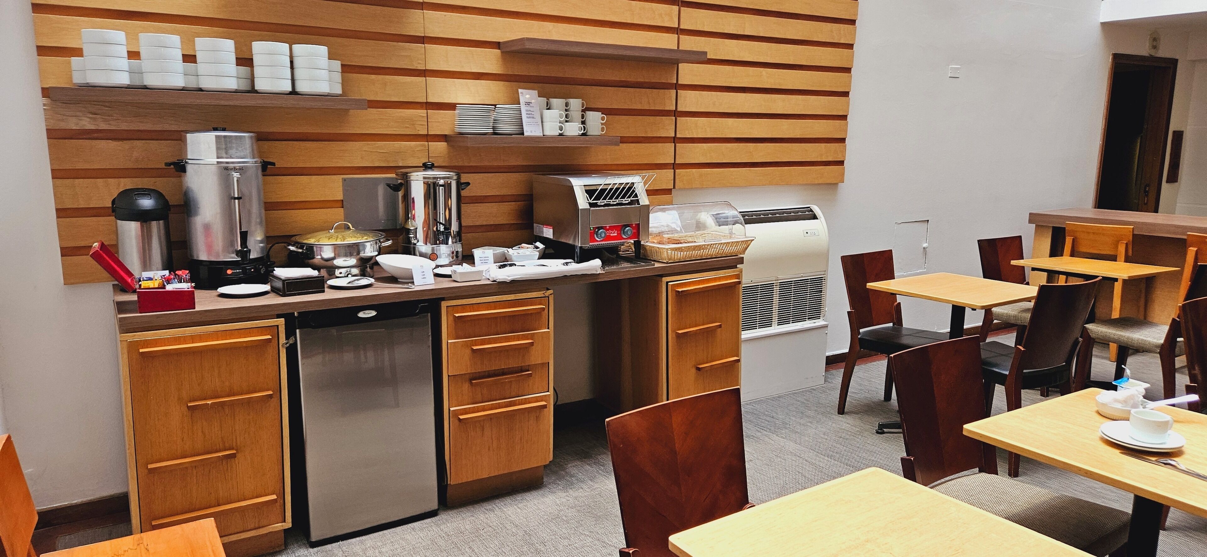 A modern kitchen area with stainless steel appliances, wooden cabinets, and a coffee station.